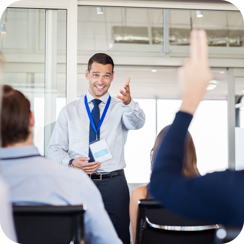 A workplace coach is asking questions in a room of delegates.